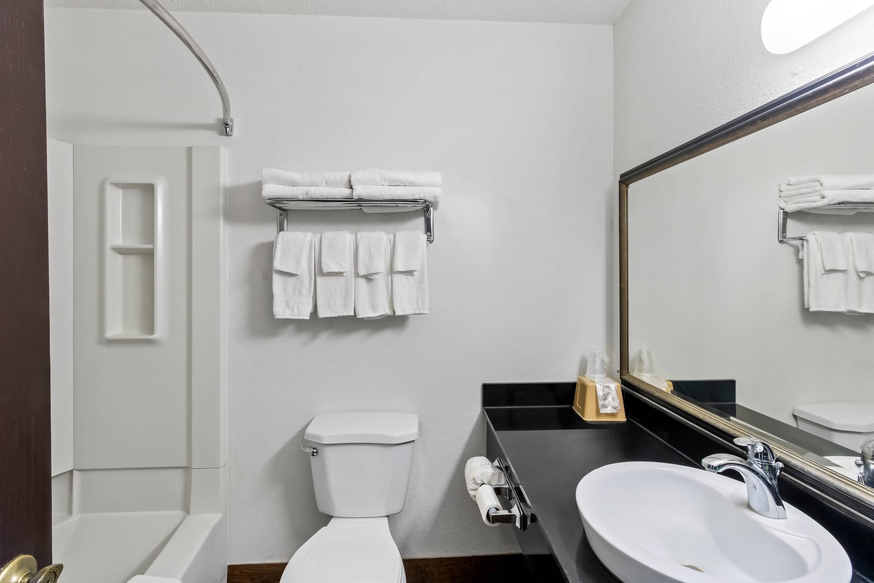 Un baño con inodoro, lavamanos y perchero para toallas.