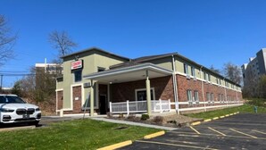A building with a sign that reads "ECONOMY" and a parking lot in front. - Suburban Studios (Coraopolis)