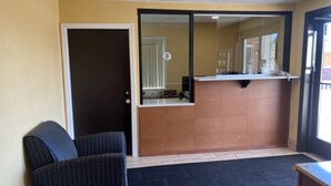 A reception area with a reception desk, a chair, and a door. - Suburban Studios (Coraopolis)