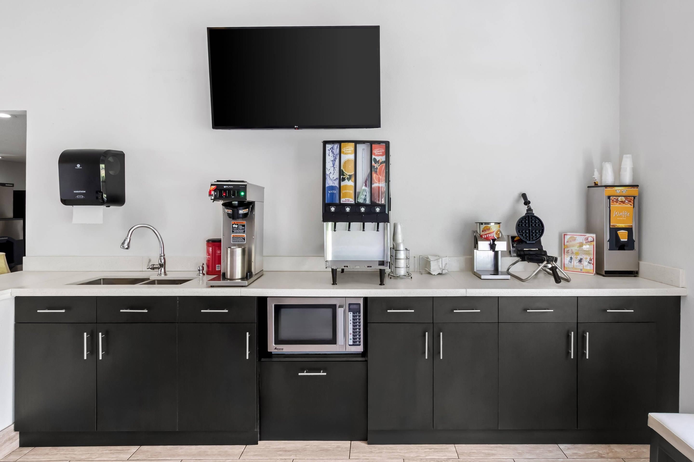 Una cocina moderna con televisión de pantalla plana, cafetera, máquina para gofres y microondas.