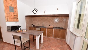 Una cucina compatta con piano di lavoro in legno, forno a microonde integrato, lavello e fornello.