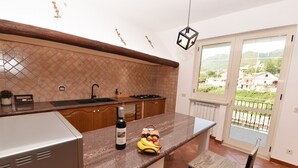 Una cucina con un piano di lavoro in granito, una bottiglia di vino e una cesta di frutta.