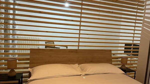 A bedroom with a wooden headboard, a bed with white bedding, and a nightstand with a lamp.