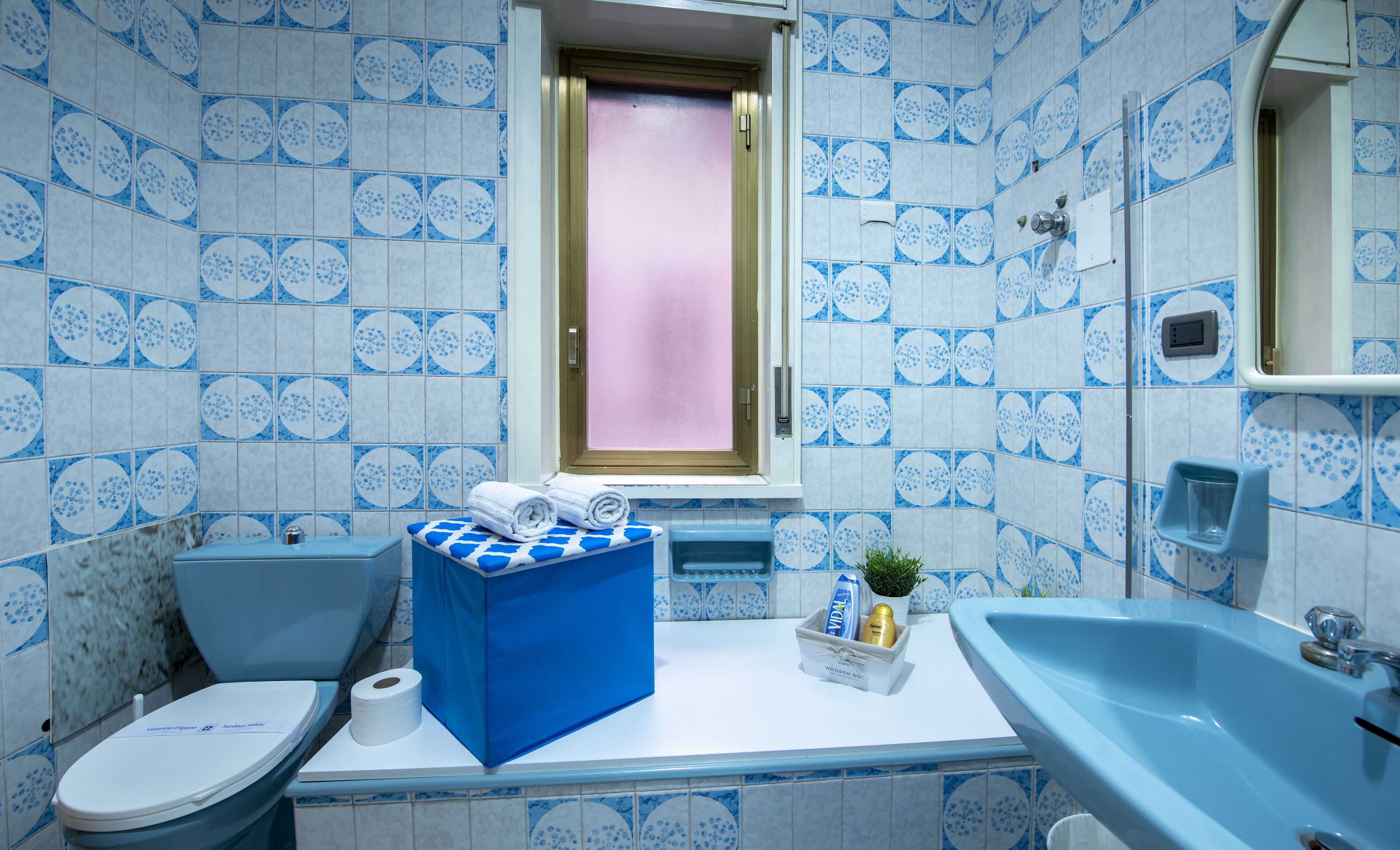 A bathroom with a toilet, sink, and window.