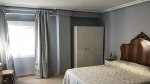 Een slaapkamer met een bed, een kledingkast, een nachtkastje en een stoel.