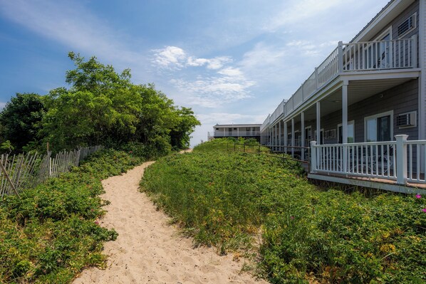 A pathway leading to a building with a balcony. - Norseman Resort (Ogunquit)