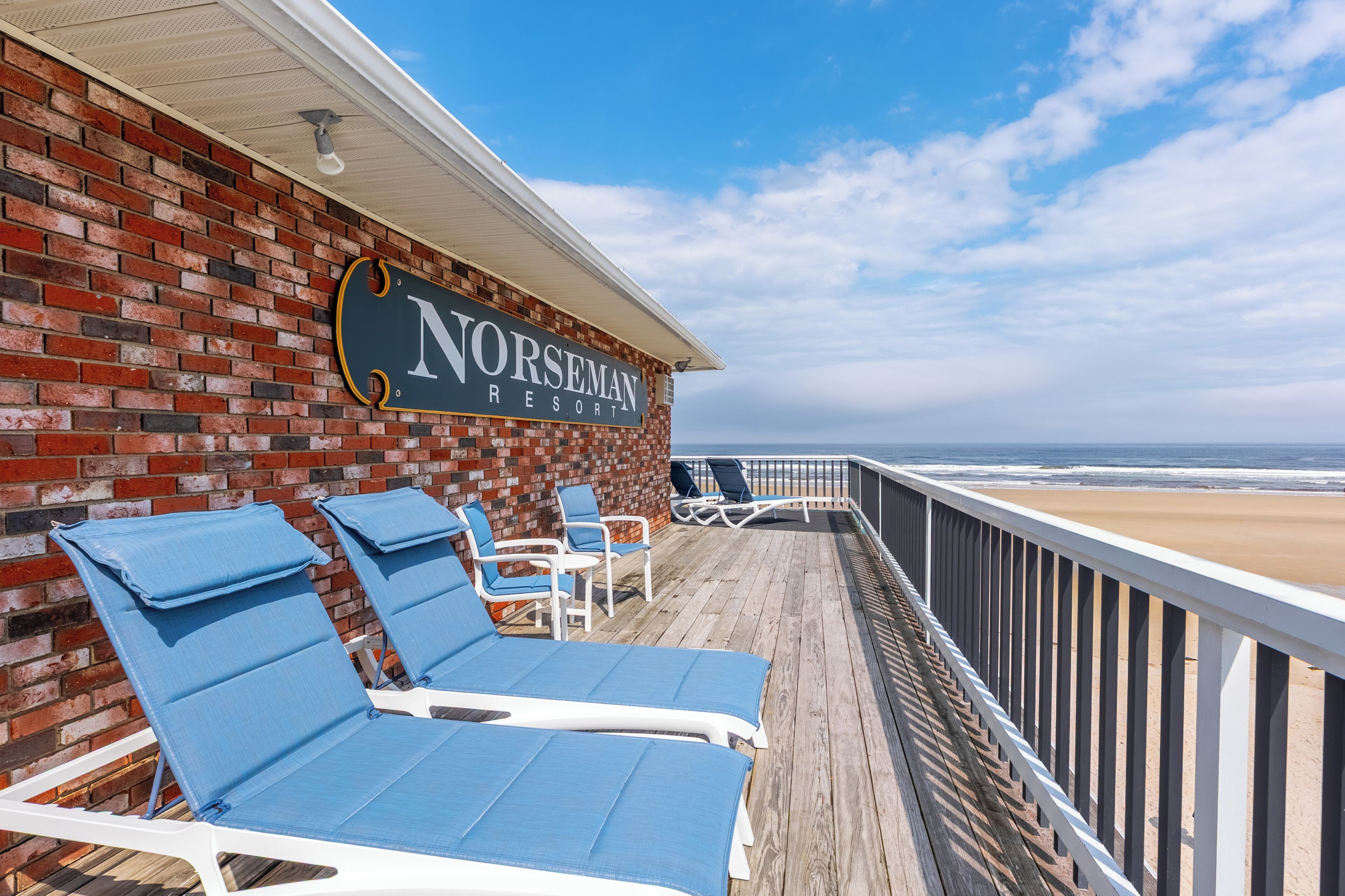 A Norseman Resort with a wooden deck, lounge chairs, and a view of the beach.