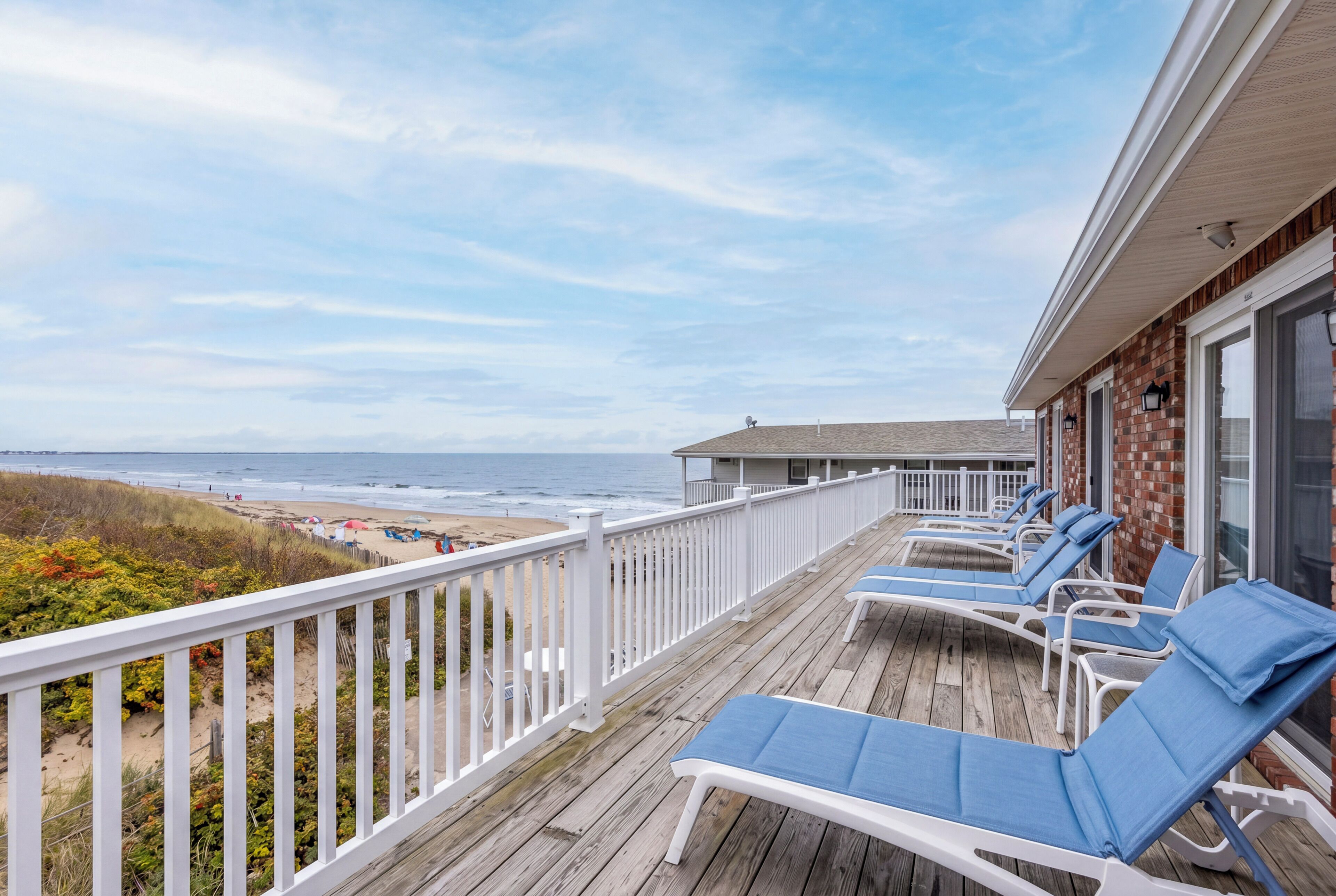 Eine Holzterrasse mit Liegestühlen mit Blick auf einen Strand.