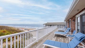 A wooden deck with lounge chairs overlooking a beach.