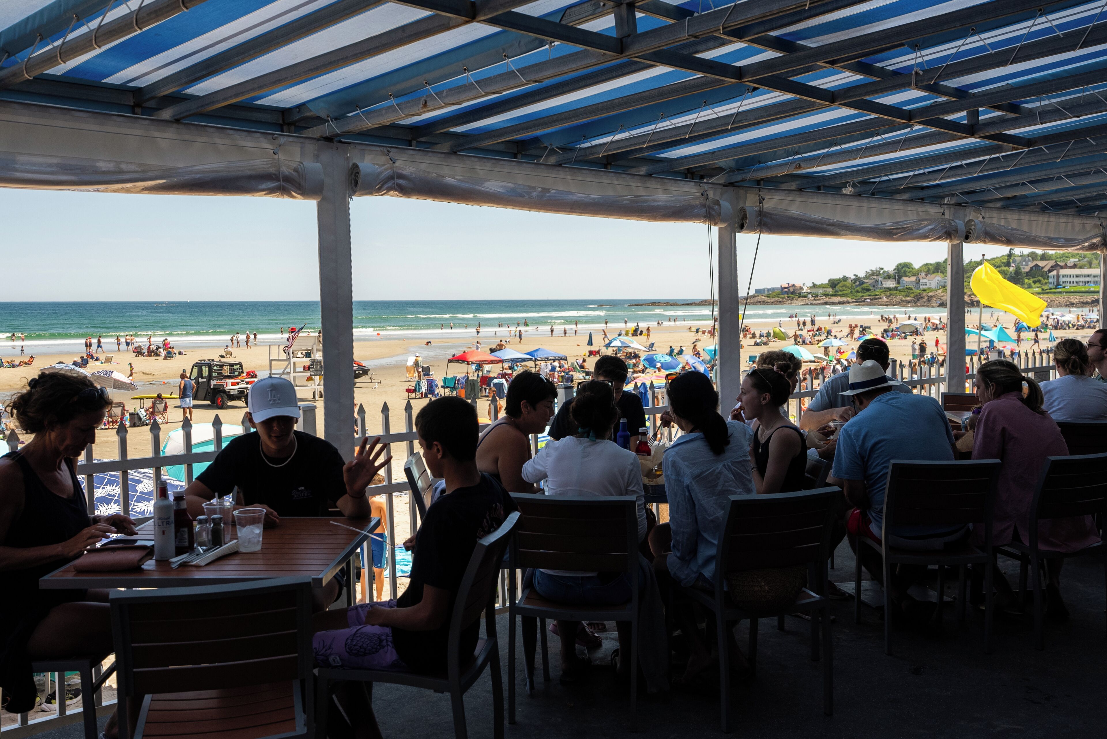 An outdoor seating area with tables and chairs overlooking a beach.