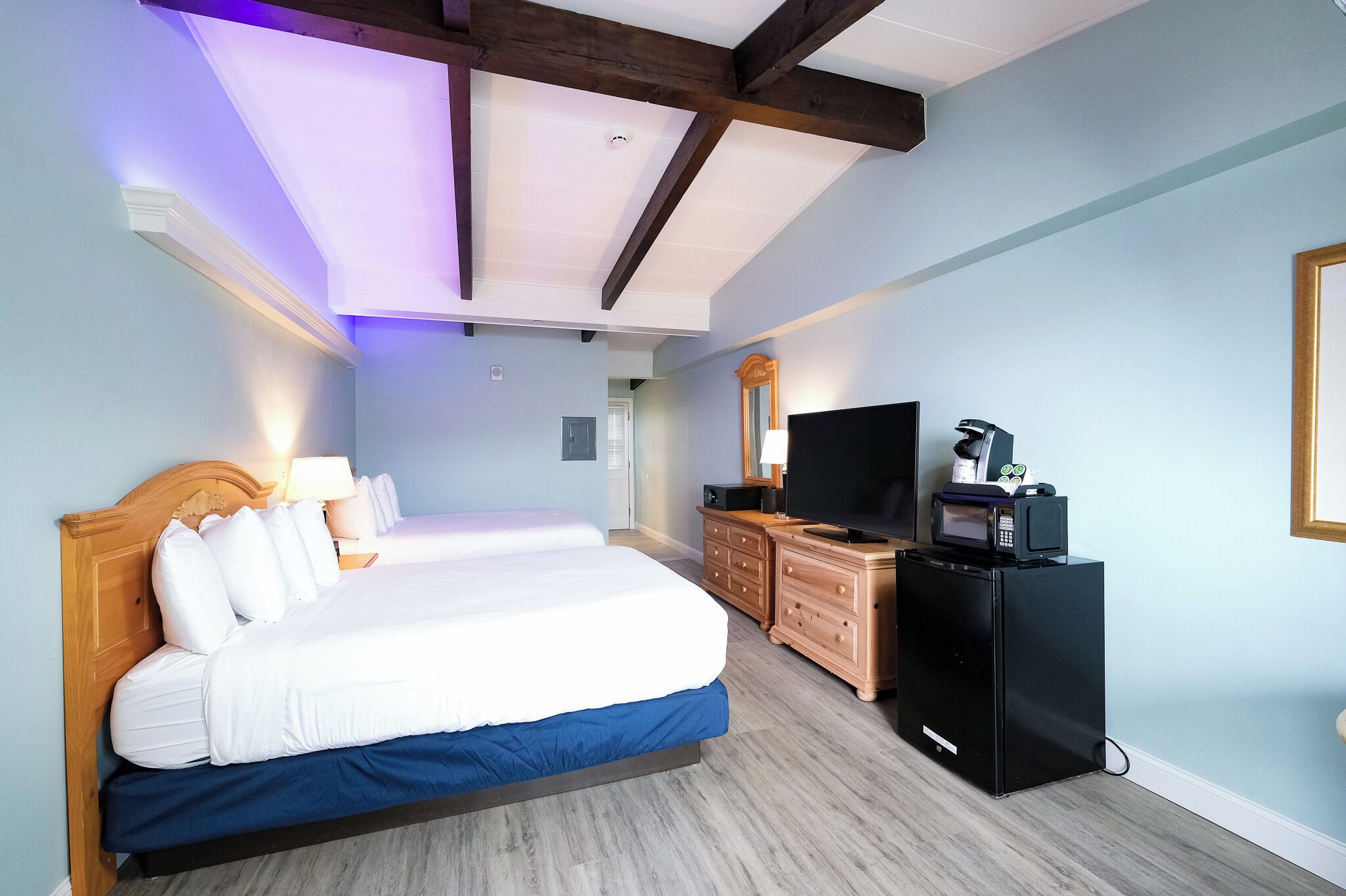 Ein Hotelzimmer mit einem großen Bett, einem Fernseher, einem Schminktisch und einer Mikrowelle.
