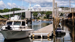 Un puerto deportivo con barcos amarrados, un muelle de madera y un puente al fondo.