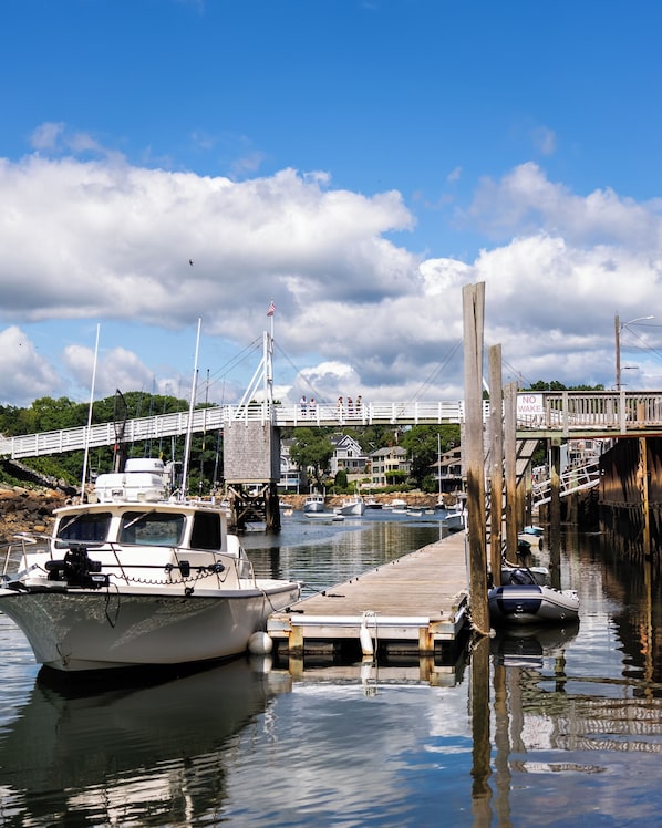 A marina with boats docked, a wooden pier, and a bridge in the background. - Norseman Resort (Ogunquit)