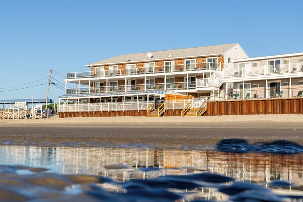 A beachfront hotel with multiple balconies, a wooden fence, and a clear view of the ocean. - Norseman Resort (Ogunquit)