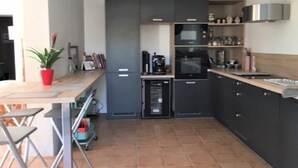 A modern kitchen with grey cabinets, a microwave, a coffee machine, and a small dining area with a table and chairs.
