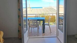 A room with a large sliding glass door leading to an outdoor patio with a table and chairs. - Spacious cocoon in Narbonne - with sea view (Narbonne)