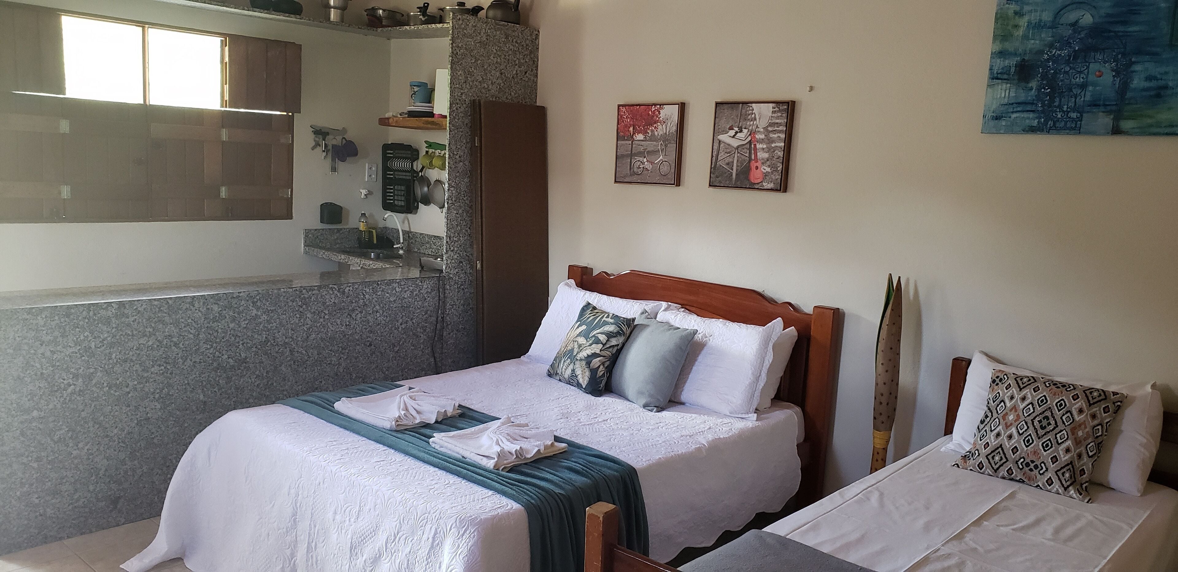 Een hotelkamer met een bed, een bijzetbed, een badkamer met een wastafel en een spiegel. Twee schilderijen hangen aan de muur.