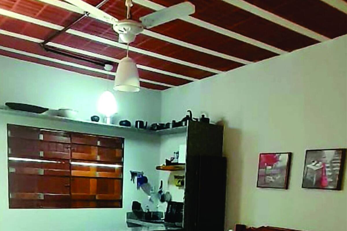 A bedroom with a bed, a desk, a chair, a ceiling fan, and a window.