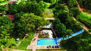 An aerial view of a resort with a swimming pool, a slide, and lush greenery.