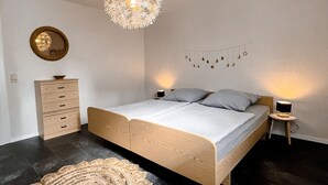 A bedroom with a bed, bedside table, lamp, wall decor, and a rug. - Cozy vacation apartment for 4 people (Baumholder)