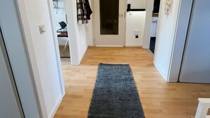 A hallway with a dark rug, wooden flooring, white walls, and a door at the end. - Cozy vacation apartment for 4 people (Baumholder)