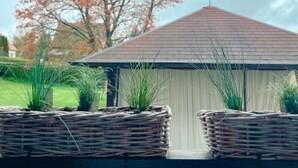 A small chapel with a cross on the roof, surrounded by greenery and a tree with red leaves. - Cozy vacation apartment for 4 people (Baumholder)