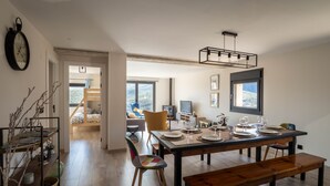 A modern dining area with a wooden table set for four, a bench, and a view of the outdoors. - The Moradel Moncayo  (Añón de Moncayo)