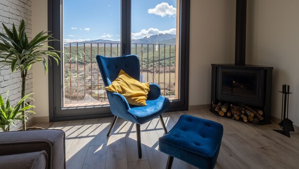 A balcony with a blue chair and ottoman, a fireplace, and a view of mountains. - The Moradel Moncayo  (Añón de Moncayo)