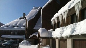 A snow-covered building with a sloped roof, a parked car, and a pile of snow in front. - Le charmant Songe en Chartreuse (Saint-Pierre-de-Chartreuse)