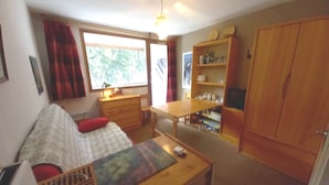 A compact room with a bed, a desk, a wooden cabinet, and a window providing natural light. - Le charmant Songe en Chartreuse (Saint-Pierre-de-Chartreuse)