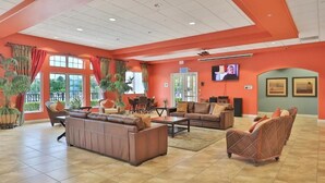 Eine geräumige Lobby mit hoher Decke, großen Fenstern und einer Sitzecke mit Sofas und Sesseln.