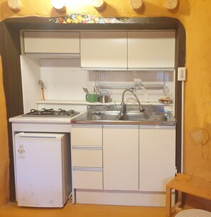 A compact kitchen with a refrigerator, stove, sink, and cabinets. - Red Clay Pension (Gangneung)