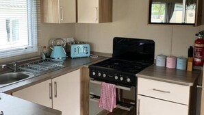Una cocina compacta con estufa, horno y un ventanal pequeño.