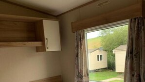 Una habitación individual con dos camas, una ventana con cortinas y un armario de madera sobre las camas.