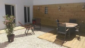 En uteplats med ett träbord och stolar, en krukväxt och ett trädäck.