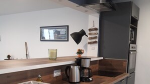 Ett modernt kök med grå skåp, en diskho i rostfritt stål, en kaffebryggare och en vattenkokare på bänkskivan.