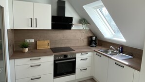 A modern kitchen with white cabinets, a black stove, and a skylight. - Generously equipped and very spacious, family vacation apartment (4) (Lembruch)