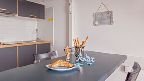 A modern kitchen with a dining table, a metal bucket with breadsticks, and a sign on the wall.