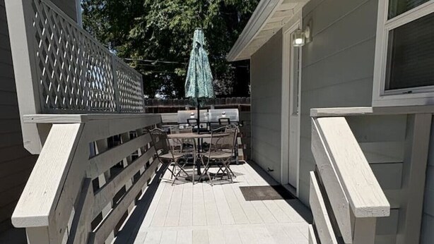 A wooden deck with a railing, a table with chairs, and an umbrella. - Downtown Paso Wine Country Retreat/2bd/2ba/Walk to the Market Walk/Downtown/Fair (Paso Robles)