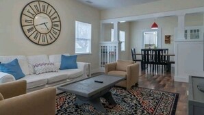 A living room with a large wall clock, a sofa with patterned cushions, a coffee table, and a patterned rug. - Downtown Paso Wine Country Retreat/2bd/2ba/Walk to the Market Walk/Downtown/Fair (Paso Robles)