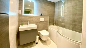 Ein modernes Badezimmer mit Waschtisch, Toilette und Badewanne.