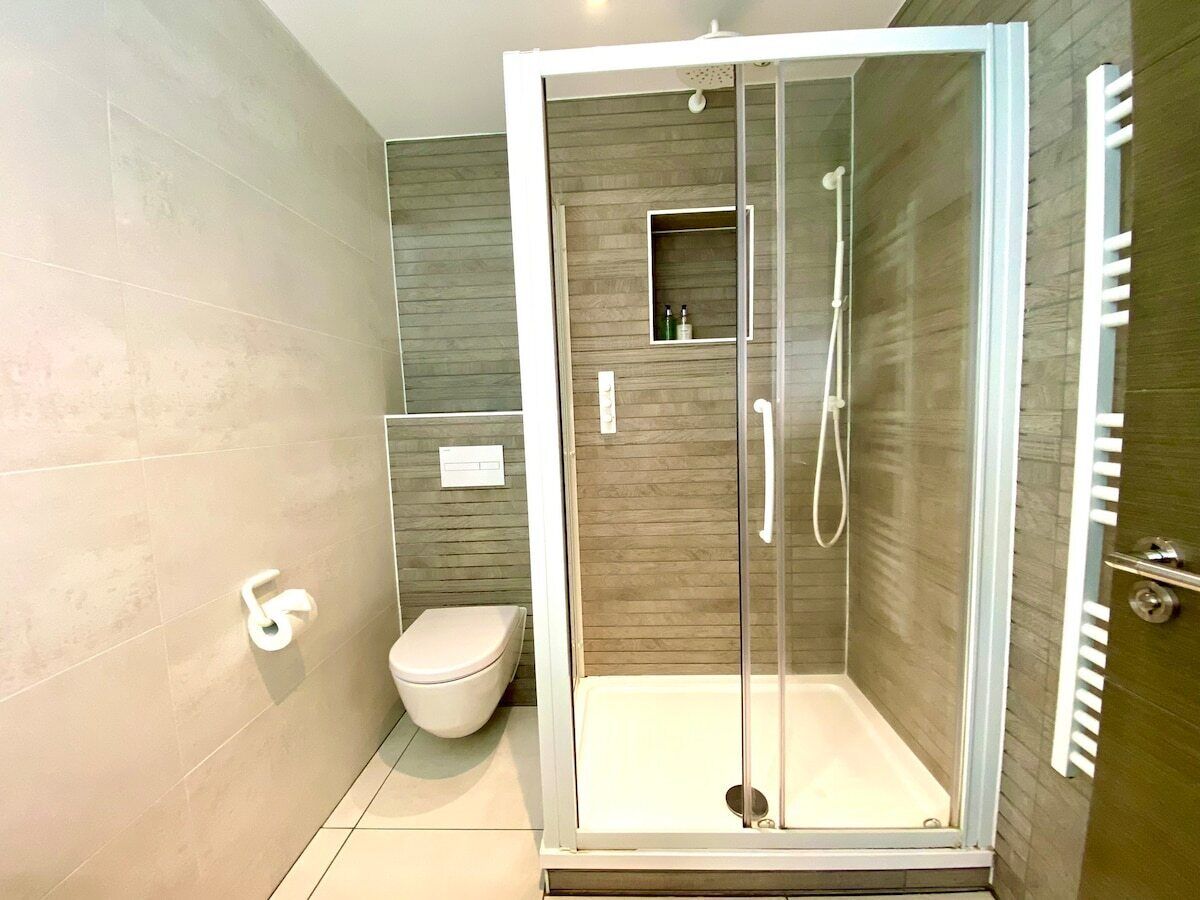 A modern bathroom with a glass-enclosed shower, a toilet, and a vanity with a mirror.