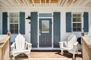 Relax on the seaside deck with Adirondack chairs, perfect for unwinding in a peaceful coastal setting.