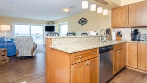 A modern kitchen with wooden cabinets, granite countertops, and stainless steel appliances. - Spacious ocean front condo in Ocean Dunes! (Kure Beach)