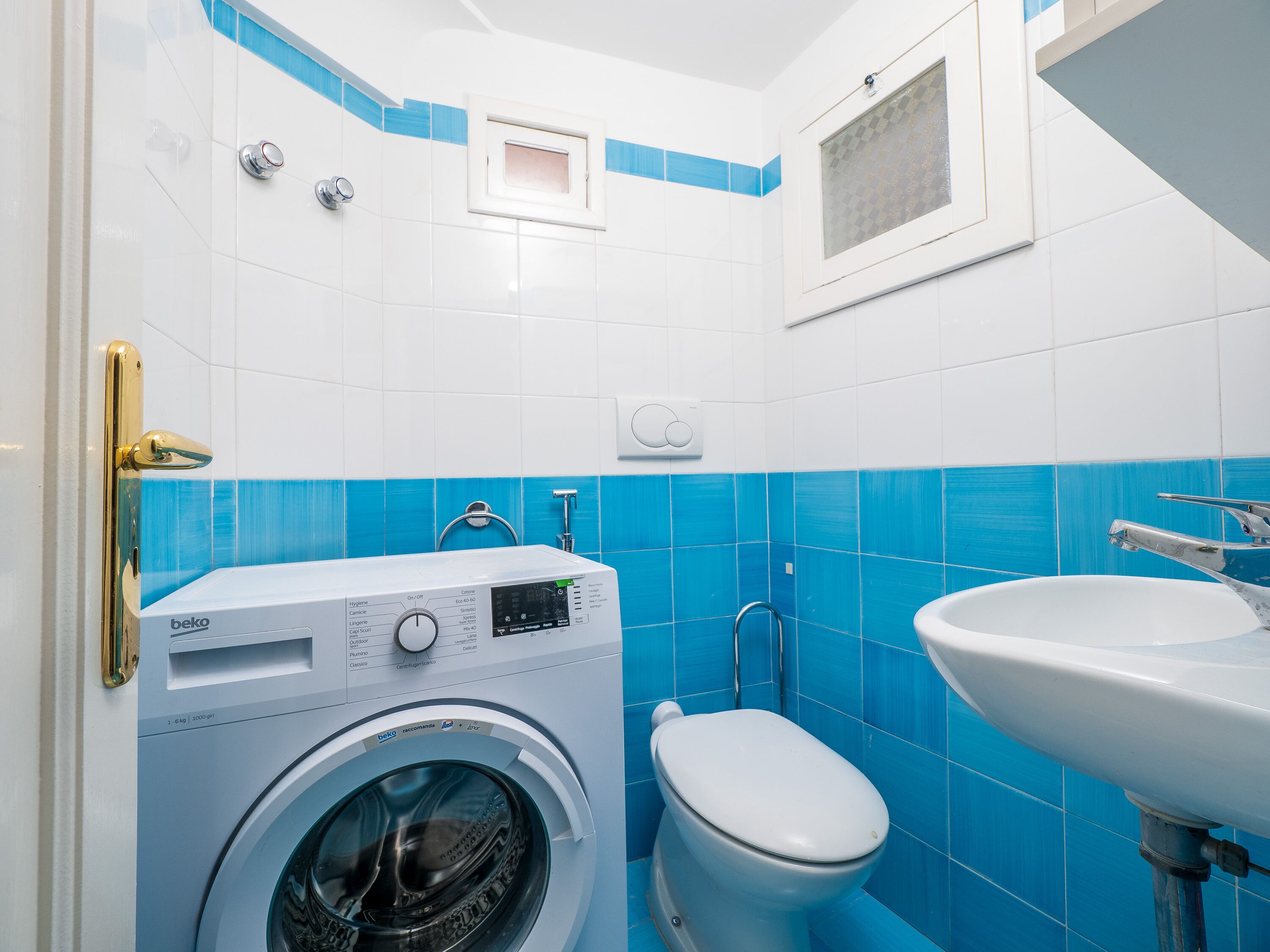 Un baño pequeño con lavadora, inodoro y lavamanos.