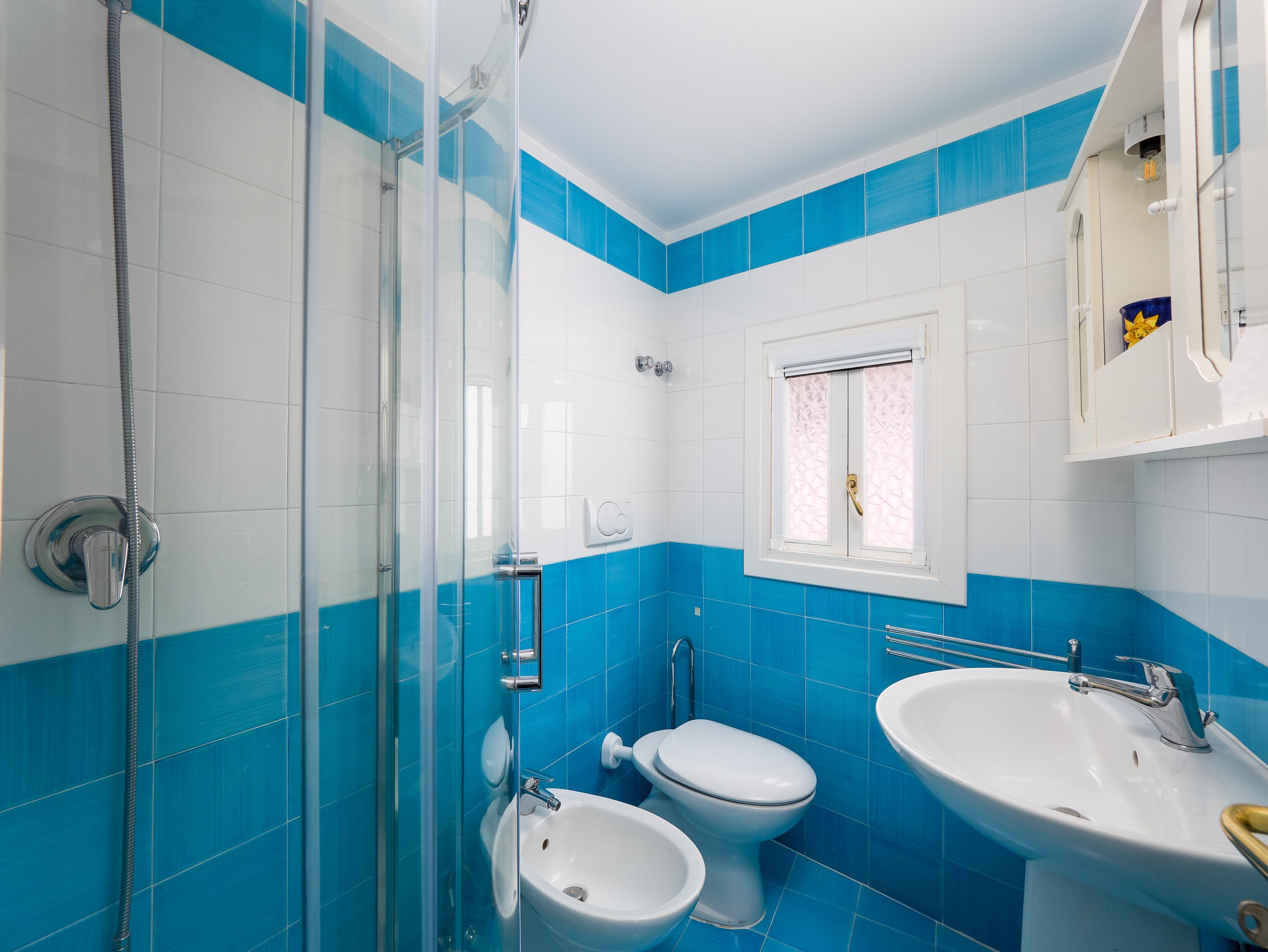 A bathroom with a glass shower enclosure, a toilet, and a sink.