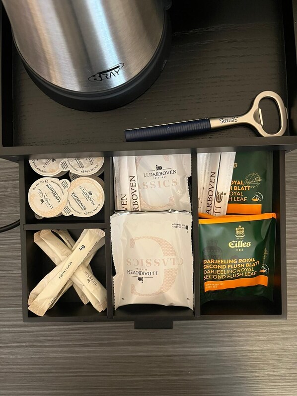 Un cajón con bolsitas de té, un par de tijeras y una olla de acero inoxidable.