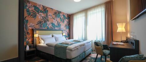 A hotel room with a large bed, a desk, a chair, and a TV.