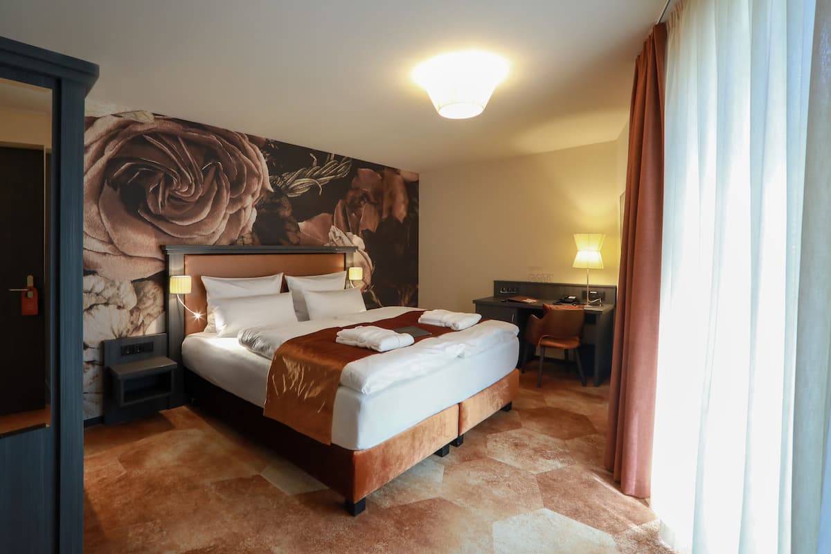 A hotel room with a large bed, a desk, and a chair.