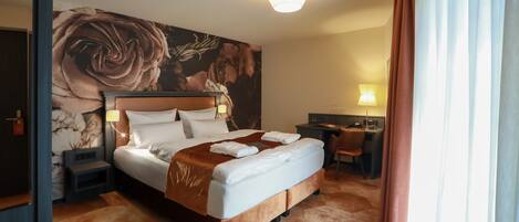 A hotel room with a large bed, a desk, and a chair.